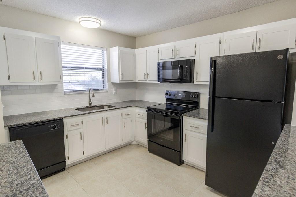 A kitchen with black appliances and white cabinets.